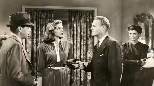 Philip Marlowe (Humphrey Bogart) faces a man pointing a gun as Vivian (Lauren Bacall) and a woman watch