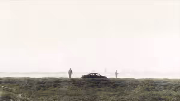 two men standing near a car on a grassy field with a distant city skyline