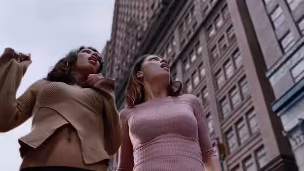 Mary Jane and a woman look upward between tall city buildings