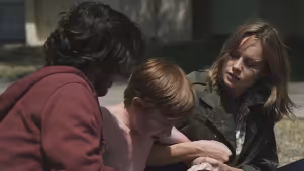 Grace (Brie Larson) comforting a shirtless boy outdoors beside a man in a hoodie