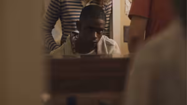 Marcus (LaKeith Stanfield) looking up from behind a wooden box with others nearby