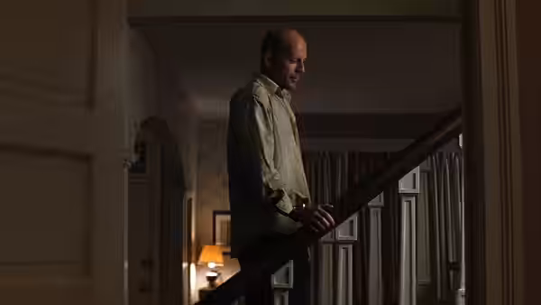 David Dunn (Bruce Willis) stands on a staircase inside a house