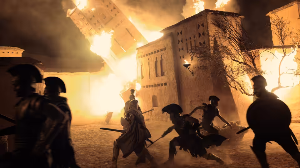 Armored warriors clash with swords before a burning fortress at night