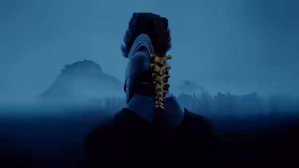 Figure with exposed spine stands facing misty mountains under a blue sky