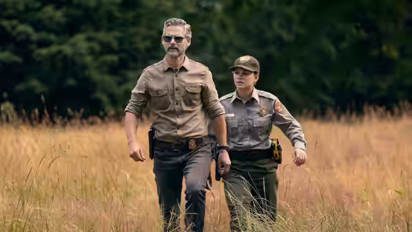 Kyle Turner (Eric Bana) walking with a female ranger through tall dry grass