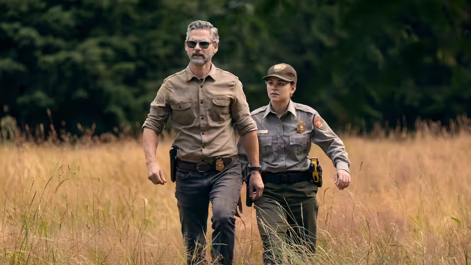 Kyle Turner (Eric Bana) walking with a female ranger through tall dry grass