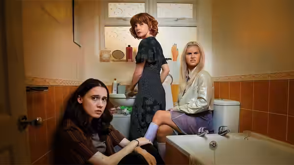 Josie (Kat Sadler) sits on the bathroom floor while Deb (Louise Brealey) stands and Billie (Lizzie Davidson) perches on the toilet