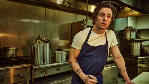 Carmy (Jeremy Allen White) leans on the counter in a stainless steel kitchen