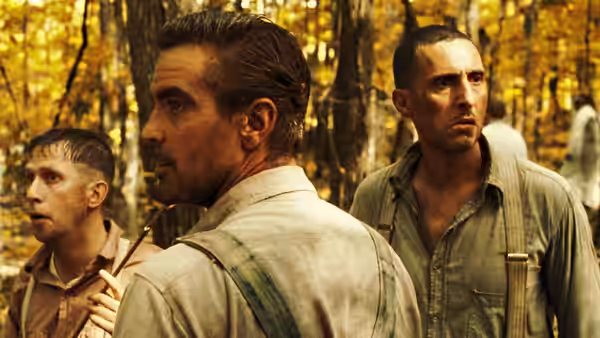 Everett (George Clooney) with a pipe walking through autumn woods