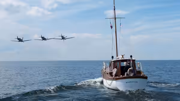 A small boat sailing on the sea with planes flying above