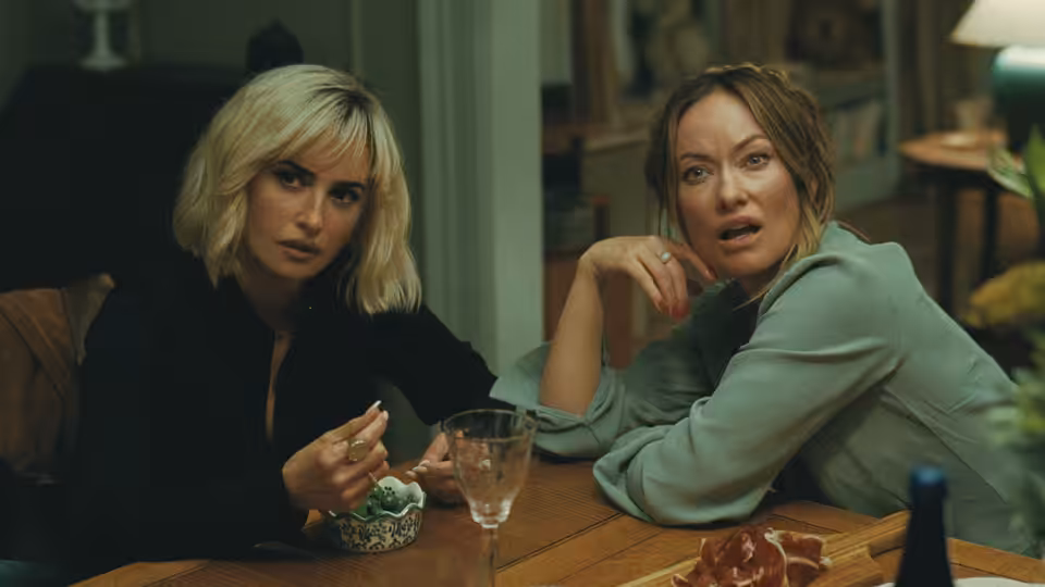 Two women seated at a wooden table with food and drinks