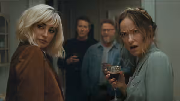 Two women in front reacting while holding a wine glass
