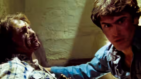Ash (Bruce Campbell) sits beside a bloodied figure in a basement