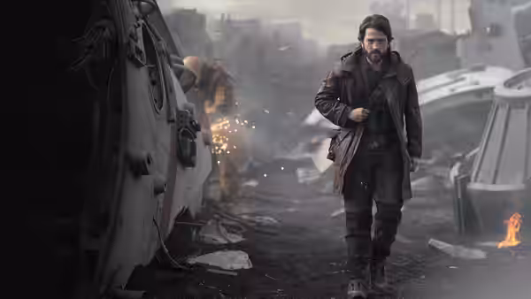 Cassian Andor (Diego Luna) walking past a damaged spacecraft in ruins