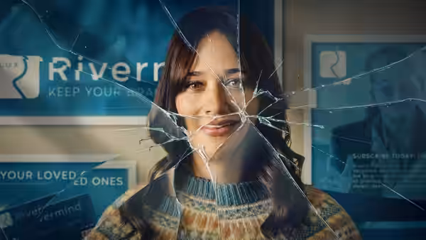 woman with brown hair smiling behind cracked glass in an office