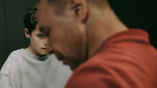 Close view of a boy in a grey sweatshirt beside a man in red