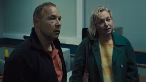 A man in a red polo shirt and a woman in a green coat standing together