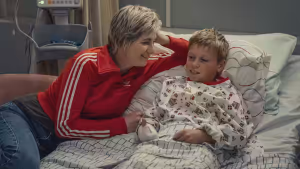 Susan McIntyre (Jodie Whittaker) smiling beside a boy in a hospital bed