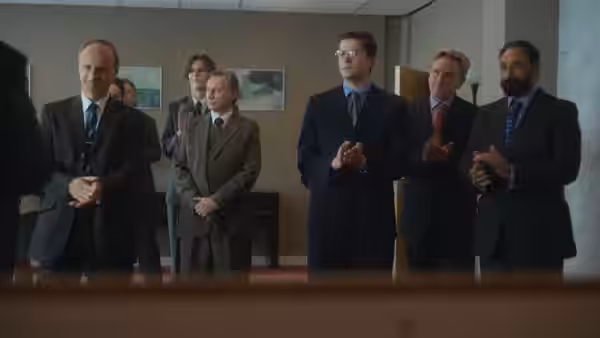 A group of men in suits clapping in a formal indoor setting