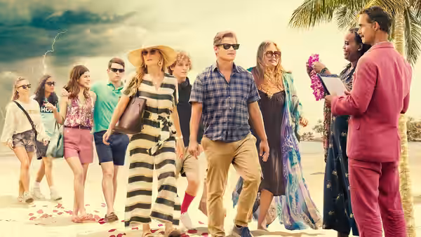 A group of resort guests walking on a petal-covered beach beside staff