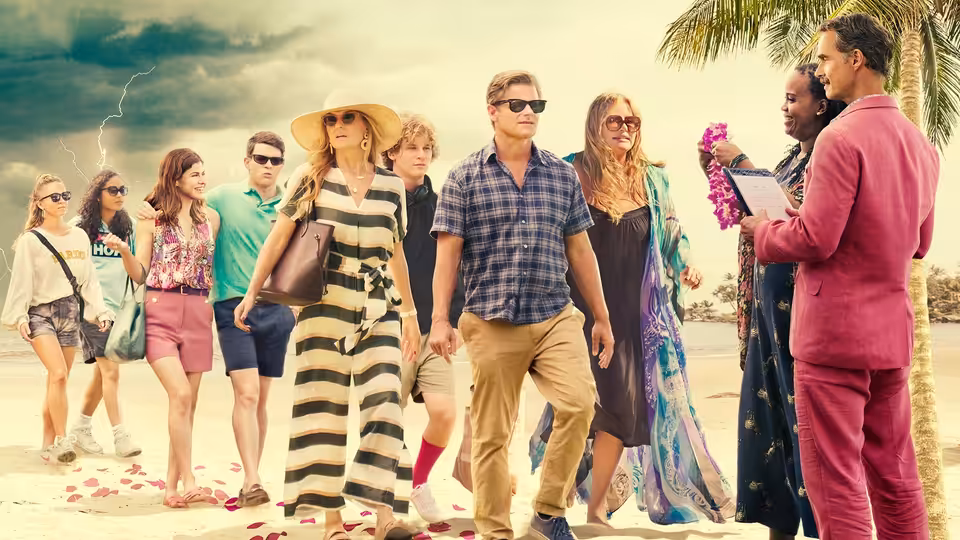 A group of resort guests walking on a petal-covered beach beside staff