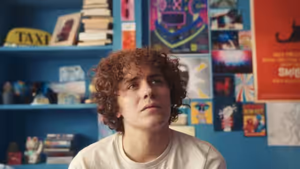 Close-up of young man with curly hair glancing to the side