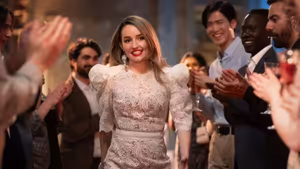 Belle Gibson (Kaitlyn Dever) walking through applauding guests at indoor event
