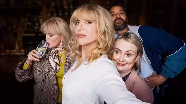 Four adults posing together for a selfie inside a bar with drinks