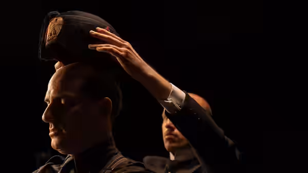 Mussolini (Luca Marinelli) having a black cap placed on his head