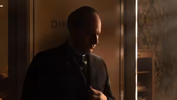 Mussolini (Luca Marinelli) adjusting his tie in an office