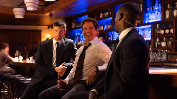 Three men in suits seated together at a bar counter