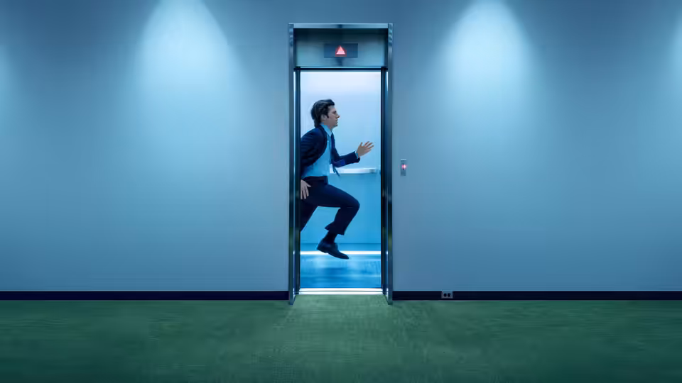 Mark Scout (Adam Scott) leaping from an elevator into a blue hallway