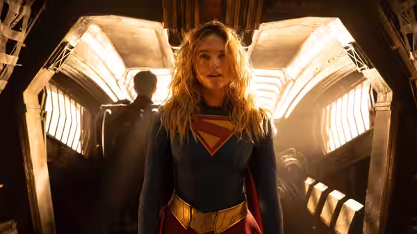 Supergirl (Milly Alcock) standing in a vast arched hall with light streaming in