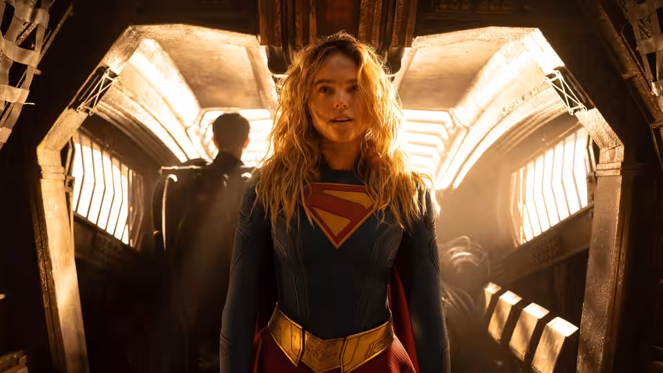 Supergirl (Milly Alcock) standing in a vast arched hall with light streaming in