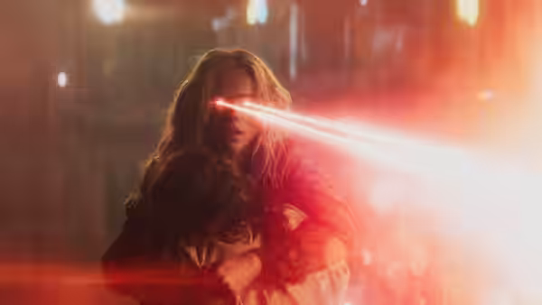 Supergirl (Milly Alcock) emitting red laser beams from her eyes while embracing someone