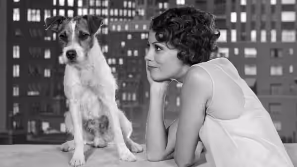 Peppy Miller (Bérénice Bejo) resting chin on hand beside dog on rooftop ledge