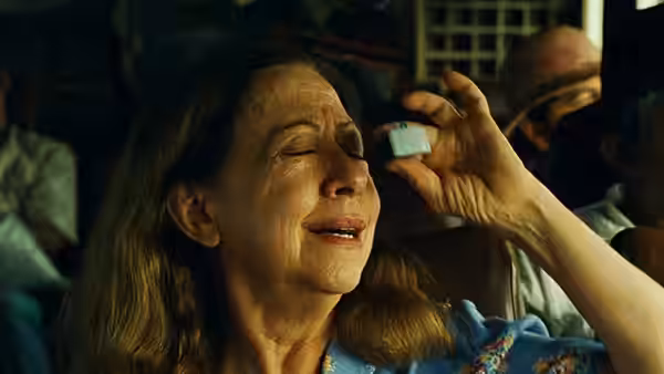 Dora (Fernanda Montenegro) holding a small object to her eye with eyes closed