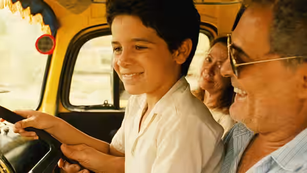 Josué (Vinícius de Oliveira) steering a yellow bus with a man beside him