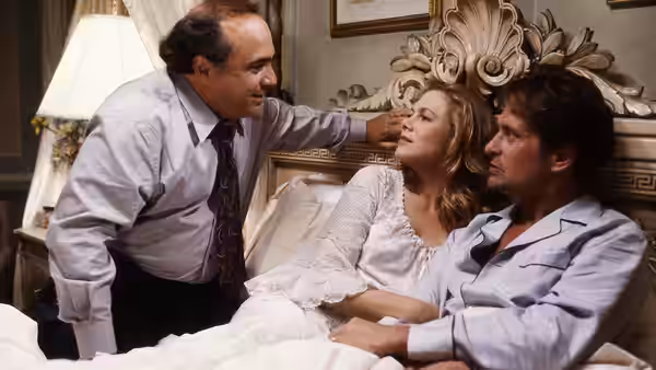 Gavin D'Amato (Danny DeVito) leans over Barbara and Oliver as they sit together in bed