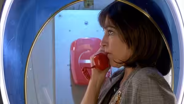Woman with short hair speaks into red telephone receiver in circular opening