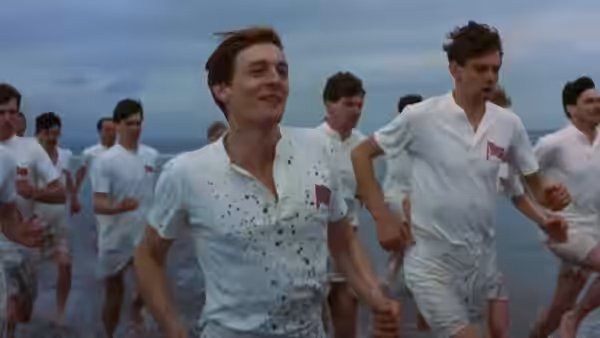 Athletes running along the shoreline on a beach under overcast skies