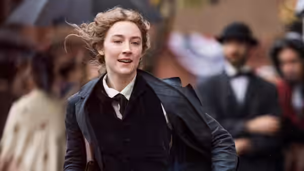 A young woman in a dark coat running on a rainy city street with windblown hair