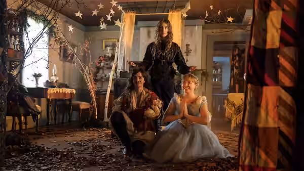 Three young women in a star-decorated room with one standing arms outstretched