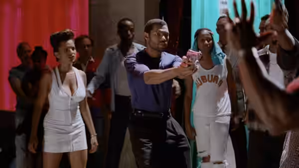 Russell Stevens Jr. (Laurence Fishburne) aims a pistol as people gather in a crowded room