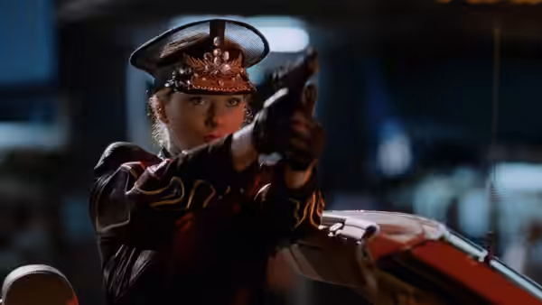A woman in an ornate uniform aims a pistol beside a vehicle