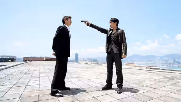 Andy Lau aiming a handgun at Tony Leung on a sunny rooftop