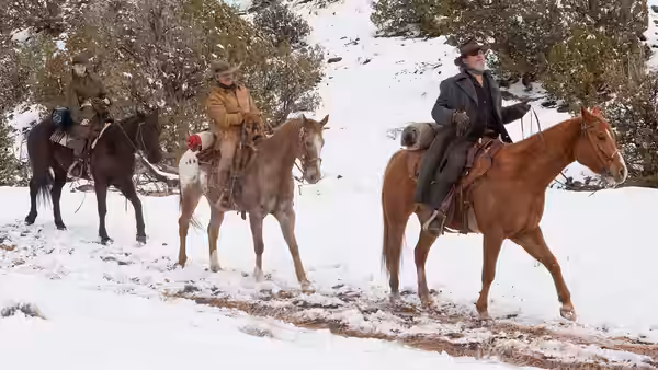 Rooster Cogburn (Jeff Bridges) riding horseback with two others in snow
