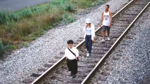 A boy, a woman and a man walking along rural railroad tracks