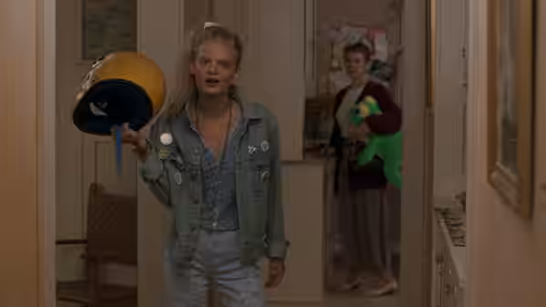Garry Buckman (Joaquin Phoenix) holds a motorcycle helmet in a doorway as a woman watches