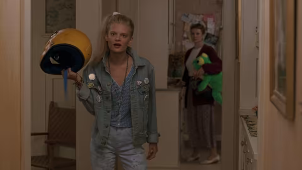 Garry Buckman (Joaquin Phoenix) holds a motorcycle helmet in a doorway as a woman watches